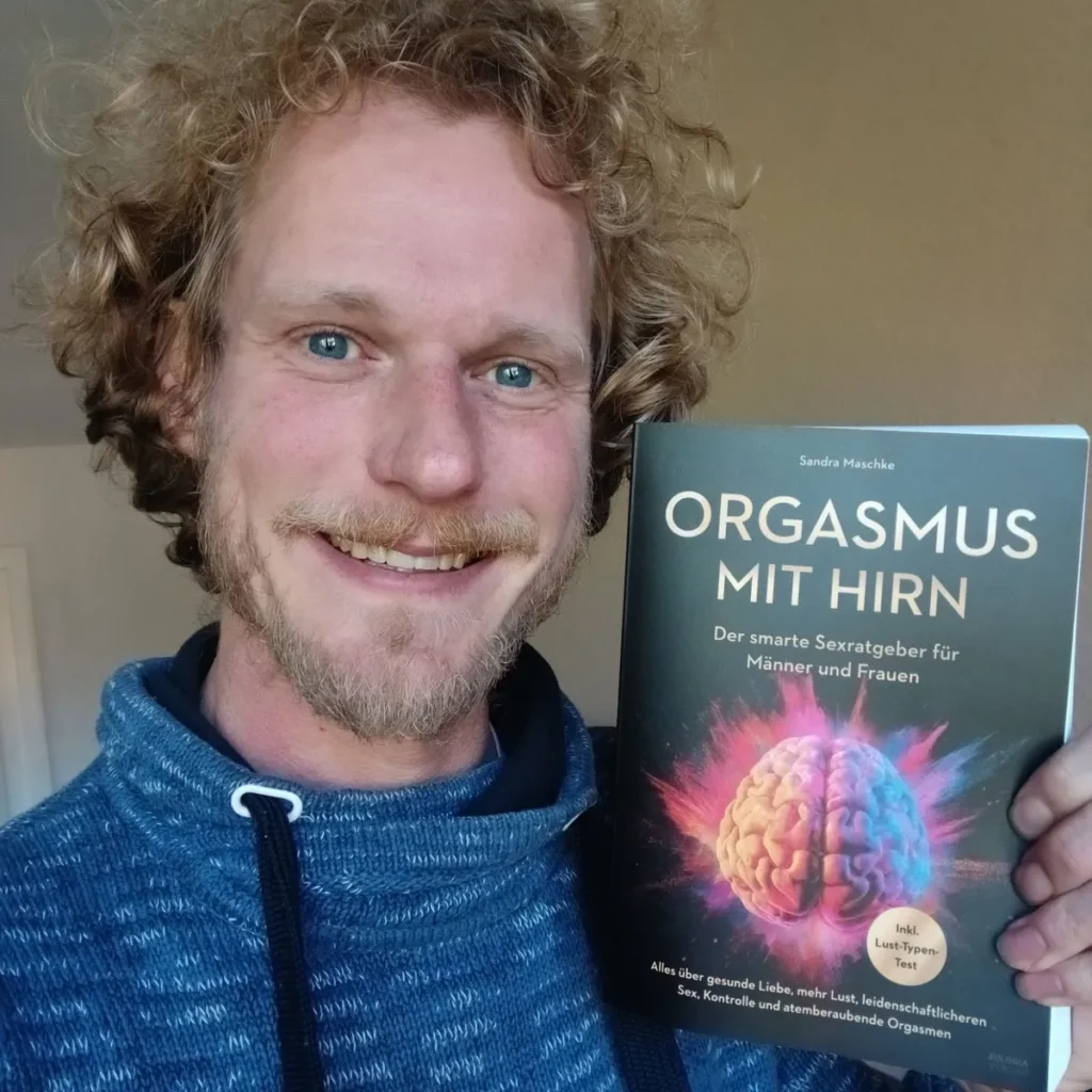 Mann hält das Buch „Orgasmus mit Hirn“ von Sandra Maschke in die Kamera